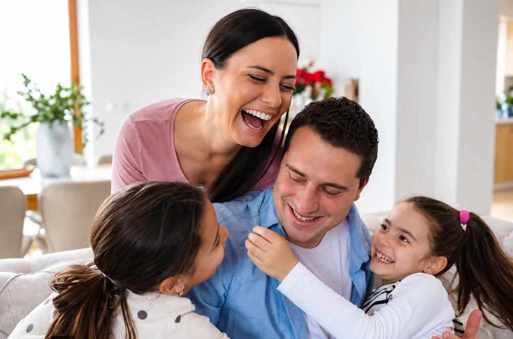 A laughing family hugging on the sofa at home