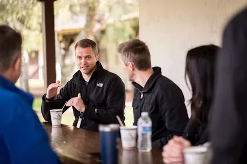 A small team talking around an outdoor table over coffee