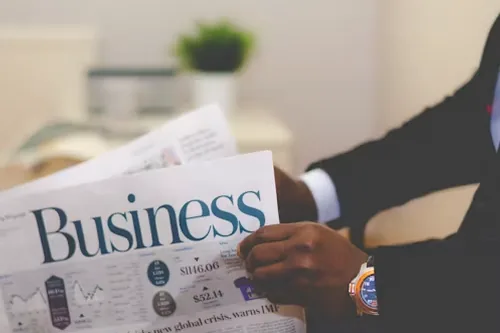 A man in a suit reading the business section of a newspaper