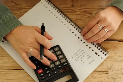 Hands working through a household budget with a calculator and notepad