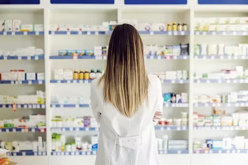 A pharmacist facing shelves of prescription medication
