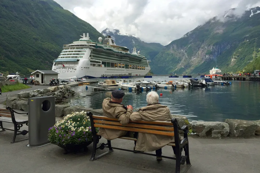 A retired couple on a bench looking out over a harbor